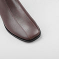 Load image into Gallery viewer, Close-up of Le Sansa Spike Choco boots showing the textured chocolate-brown leather and detailed spike embellishments.